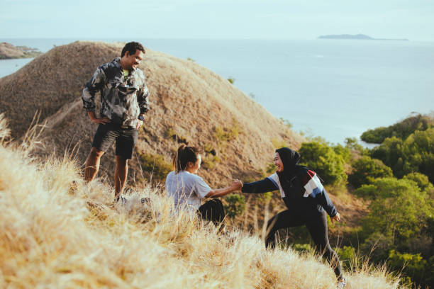 Asian young adults walking on hill watching the beach on sunrise Asian young adults walking on hill watching the beach on sunrise Hiking stock pictures, royalty-free photos & images