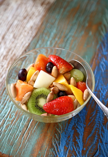 fruit salad with baru nuts and honey in glass bowl