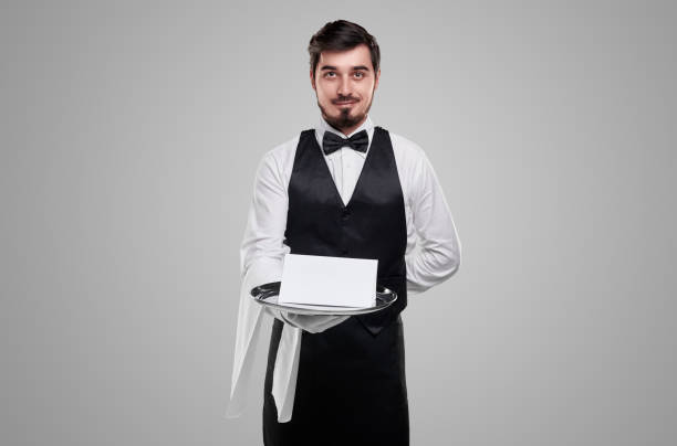 istock Smiling bearded waiter with blank paper on tray 1356594767