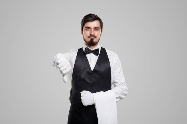 istock Waiter in uniform with thumb down on gray background 1356594787