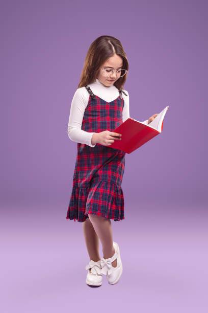 istock Smart schoolgirl in uniform reading textbook 1356594797