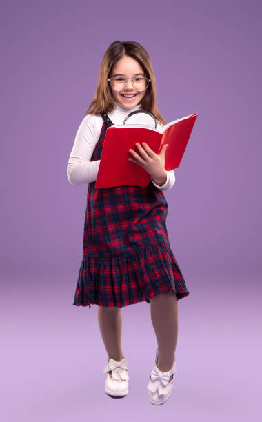 istock Clever girl with magnifier reading book 1356594805