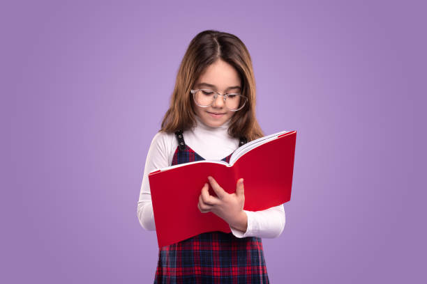 istock Clever little schoolgirl reading book 1356594806