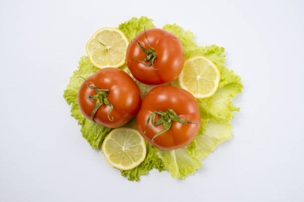 Fresh tomatoes with water drops on green lettuce