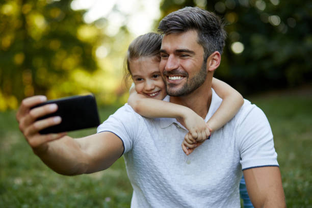 istock Father and daughter taking Selfie in the park 1356598611