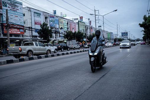 Young man jacket jean rides motorbike in Bangkok city downtown traffic street sidewalk