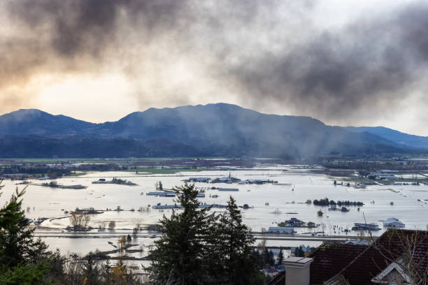 Devestating Flood and black smoke from fire in the city and farmland after storm. Abbotsford, Greater Vancouver, British Columbia, Canada - November 17, 2021: Devestating Flood and black smoke from fire in the city and farmland after storm. abbotsford canada stock pictures, royalty-free photos & images
