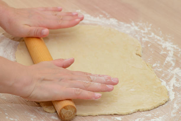 istock Women's hands roll out the dough on the table with a rolling pin 1356603319