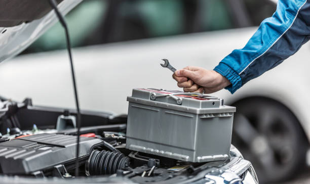 정비사는 자동차의 엔진 트렁크가 열려있는 자동차 배터리 위에 열쇠를 보유하고 있습니다. - battery replacement 뉴스 사진 이미지