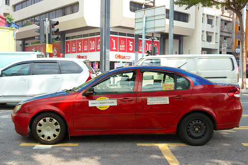 Kuala Lumpur, Malaysia - March 12, 2019: Red cab on road of Kuala Lumpur, Malaysia. Street traffic. Typical taxi running on the street downtown