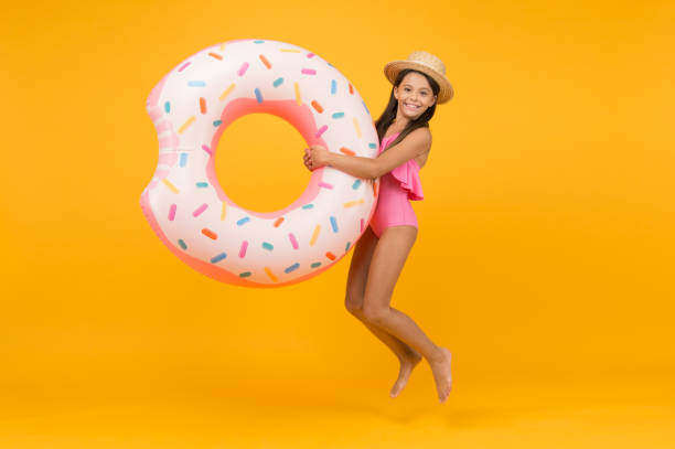 istock Summer swimsuit. summer water activities. active and energetic vacation. ready for playing and sunbathing. Surfing in the sea. little girl and rubber ring. jumping kid in swimwear at swimming pool 1356612921