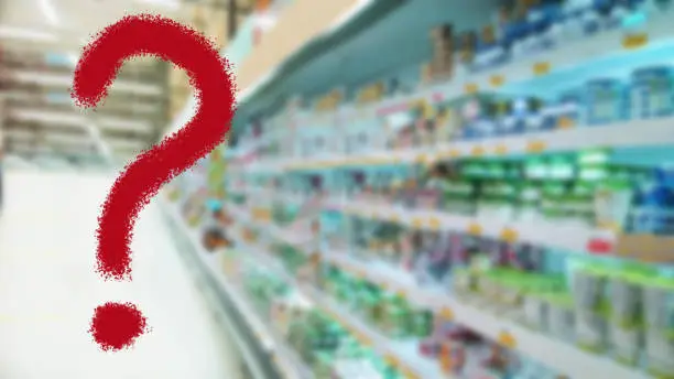 Photo of Large red question mark on abstract blur supermarket background. Defocused shelves with products. Grocery shopping. Store. Retail industry. Food. Inflation and problem concept. Finance and Economy.