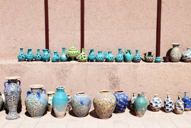 Traditional iranian souvenirs - colorful clay pots and jugs, Iran Traditional iranian souvenirs - colorful clay pot and jug, Yazd, Iran. Clay jugs of various shapes of green and blue colors on a shelf near the adobe wall. Copy space for text persian pottery stock pictures, royalty-free photos & images