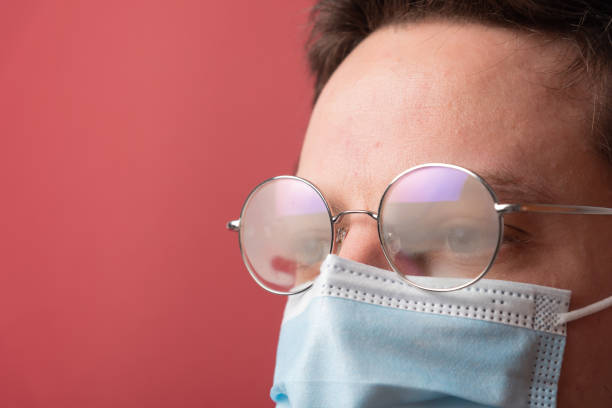 Young man with misted up eyeglasses due to facemask stock photo