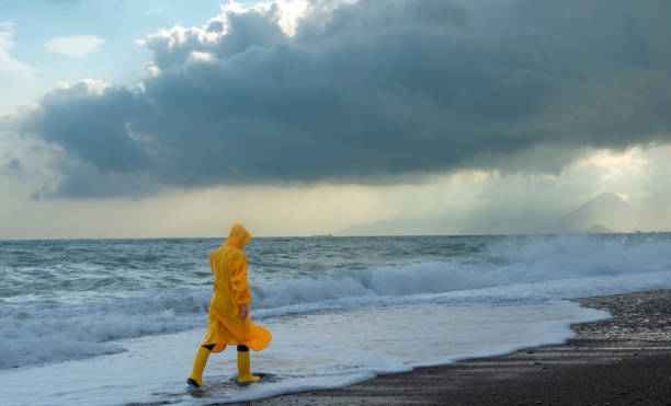 istock Storm clouds, high waves and man in yellow raincoat. 1356616034