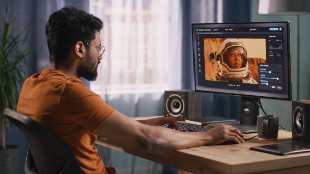 Indian retoucher working with astronaut photo Side view of bearded Indian man using retouching software on computer to edit picture of cosmonaut during work in home office motion picture screen stock pictures, royalty-free photos & images