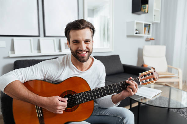 istock Happy man playing on guitar. Looking at camera. 1356616516