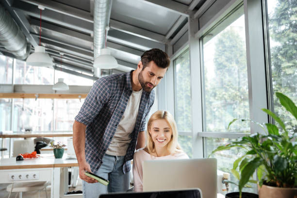 istock Happy two colleagues in office coworking while using laptop 1356619788