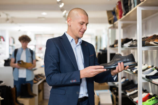 istock Smiling man looking for classic shoes in shoe store 1356622050