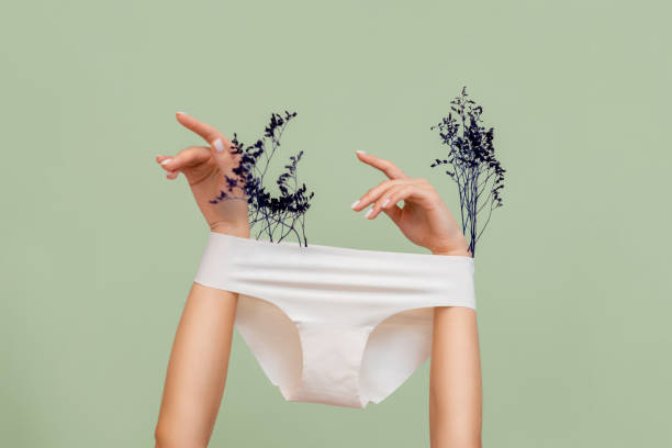 as mãos femininas, que seguram plantas secas, braços estão usando calcinha branca. fundo verde. o conceito de depilação de áreas íntimas e ginecologia - women panties one person sensuality - fotografias e filmes do acervo