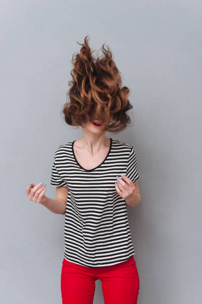 Happy young lady standing over grey wall shaking hair. Picture of happy young lady standing over grey wall and shaking hair. gray hair young woman stock pictures, royalty-free photos & images
