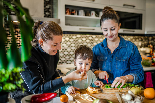 istock Same sex couple and their child preparing dinner in kitchen 1356630477