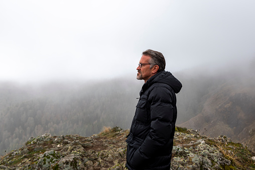 lonely mature man looking at misty mountains