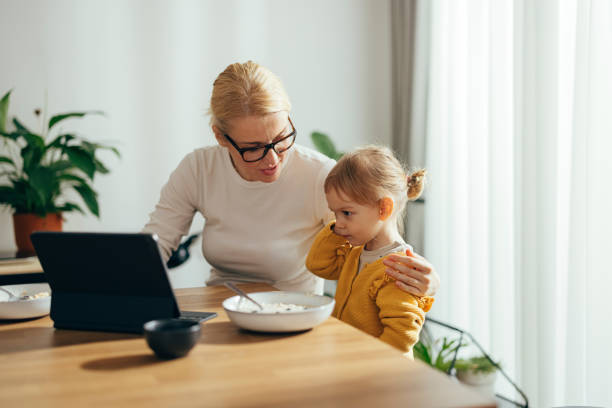 istock Baby Girl and Her Mother Using the Tablet While Also Having Breakfast at the Table 1356633084