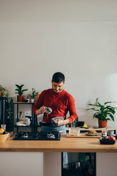 istock Handsome Cheerful Man Preparing a Meal at Home 1356633131