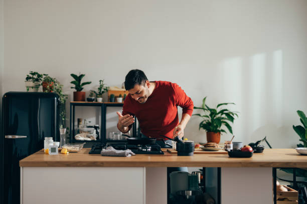 istock Handsome Cheerful Man Preparing a Meal at Home 1356633150