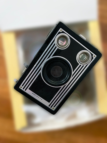 Art Deco style vintage Brownie Target 16 camera atop a gift box blurred background.