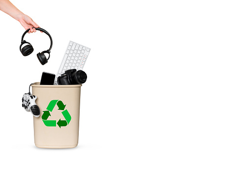 hand throws headphones in a bucket with other gadgets for recycling.