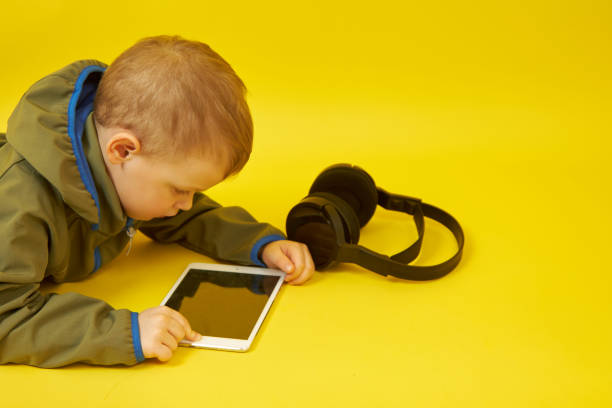 istock A child lying down uses a digital tablet on a yellow background 1356635585