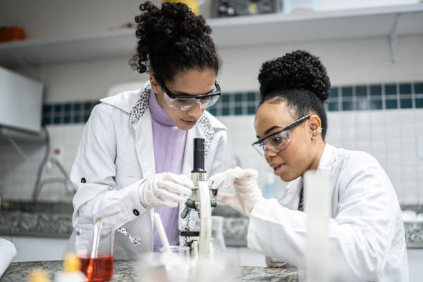 estudiante adolescente usando el microscopio en el laboratorio - women scientist indoors science fotografías e imágenes de stock