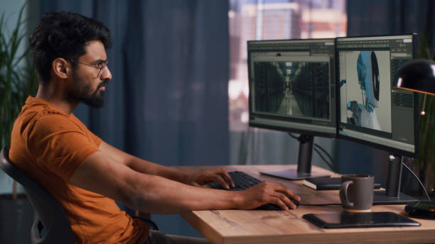 Indian man creating 3D model at home Side view of Indian 3D designer creating and rendering model of futuristic robot for movie on computer during work at home animator stock pictures, royalty-free photos & images