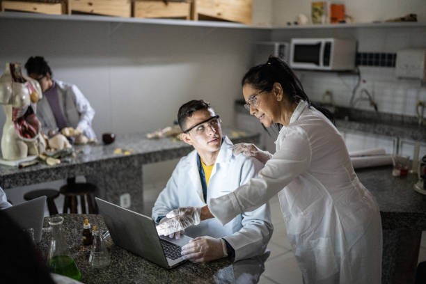 istock Chemistry teacher teaching students in the lab at school or university 1356640247