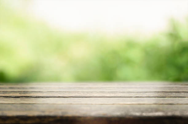 istock Wooden table top with green background 1356641674