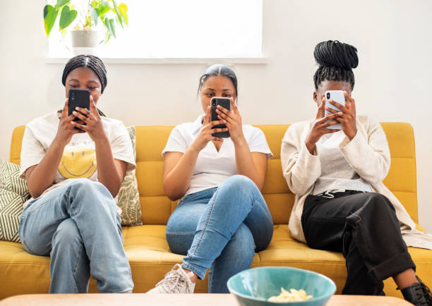 Group of teenage girls checking their phones on a sofa stock photo