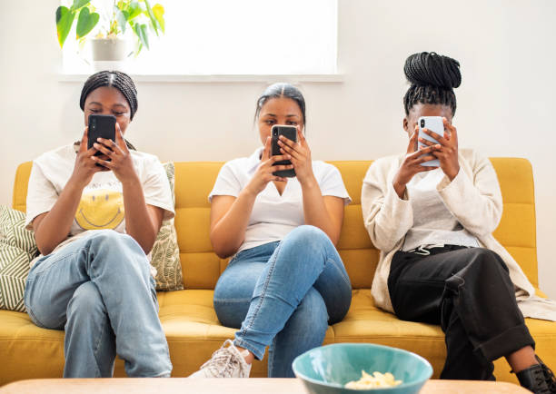 grupo de adolescentes checando seus telefones em um sofá - fileshare - fotografias e filmes do acervo