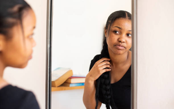 Teen girl examining her complexion in a bedroom mirror stock photo