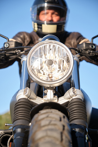 Front view of a motorcycle with spotlight on and rider out of focus.