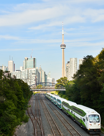 Commuter train traveling on railway tracks from the city of Toronto with the CN Tower in the background