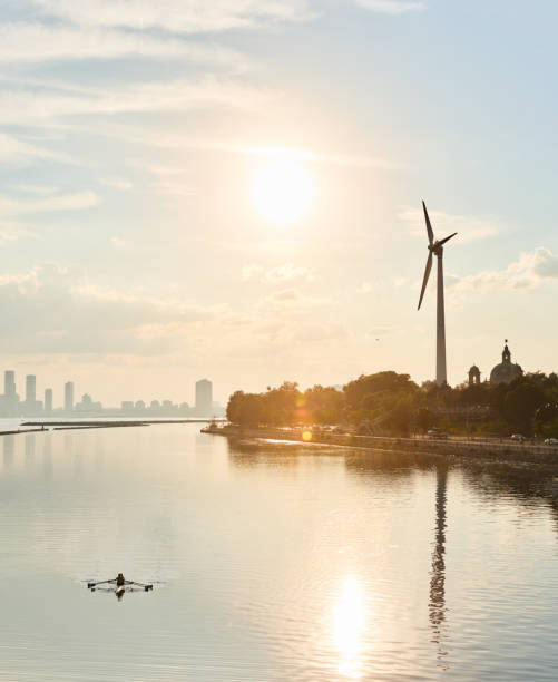 People sculling in an urban lake next to a wind turbine Two people sculling in a lake next to a wind turbine with a city in the background on a late summer afternoon sustainable energy toronto stock pictures, royalty-free photos & images