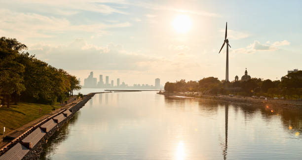 Wind turbine by an urban lake in summer Solitary wind turbine at the edge of a lake with a city in the background in the summertime sustainable energy toronto stock pictures, royalty-free photos & images