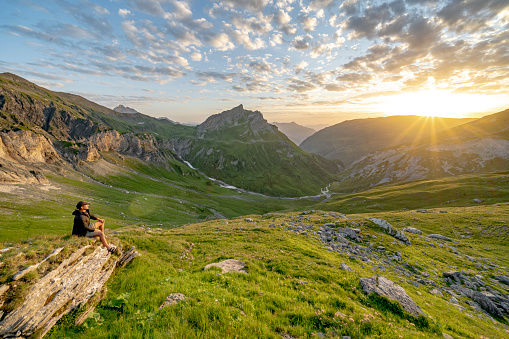 A hiker sat watching the sunset in the French Alps during the Tour Du Mont Blanc hike