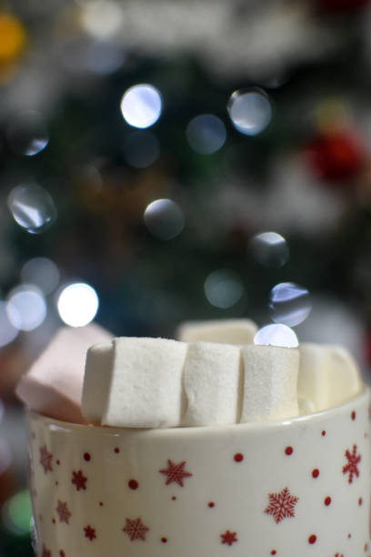 istock Marshmallows in a mug with hot cocoa in front of a Christmas tree 1356647997