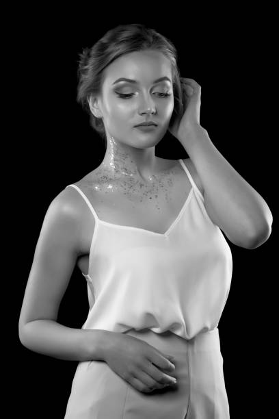 istock Stylish blond lady wears white silk dress posing in the shadow at studio 1356649513