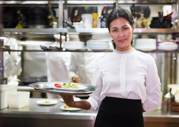 istock Smiling waitress with ordered dishes in kitchen of restaurant 1356649610