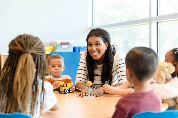 istock Female teacher enthusiastically explains the solar system to kindergarten students 1356661327