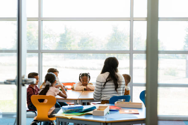 istock Preschool children sit quietly at a table with teacher 1356661340